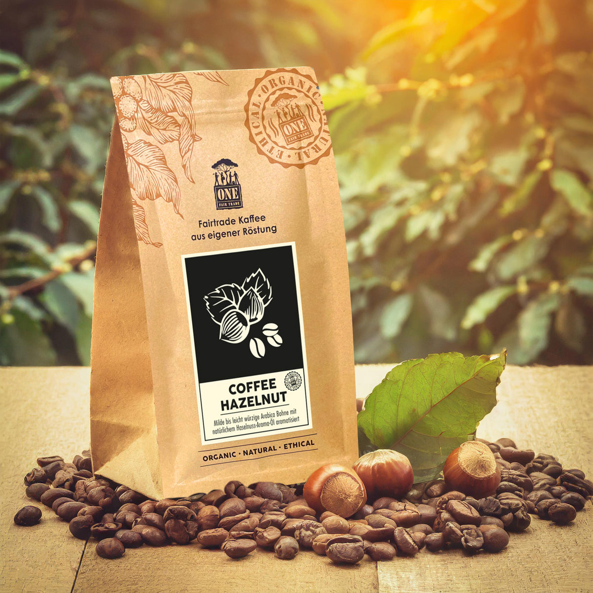 Coffee Hazelnut Tüte mit fairtrade Kaffeebohnen und Haselnüssen als Dekoration. Der Hintergrund sind verschwommene Haselnussbaumblätter.